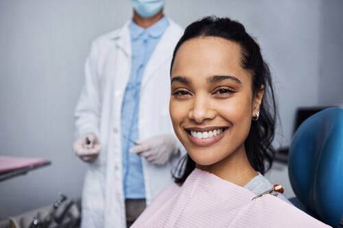 Smiling woman sitting in a dental chair beside her dentist