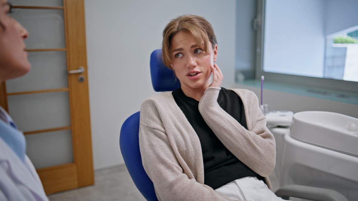 Adult patient experiencing jaw discomfort while speaking with a dentist during a consultation in a dental office