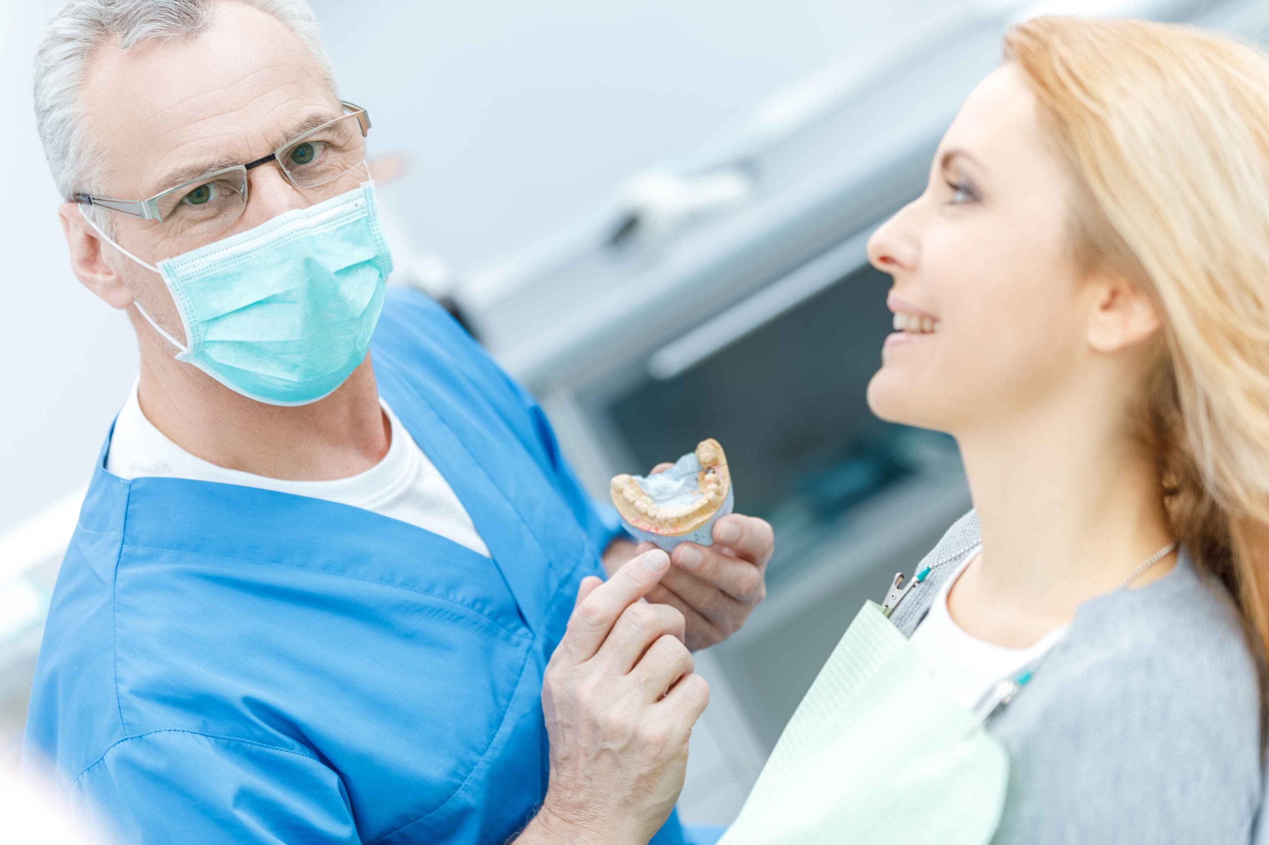 Dentist explaining a dental model to a patient during consultation.
